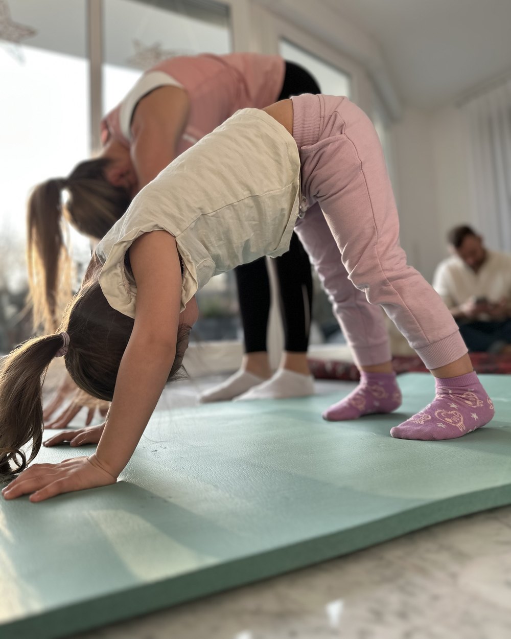 Zwei Kinder machen den herabschauenden Hund auf einer Yogamatte