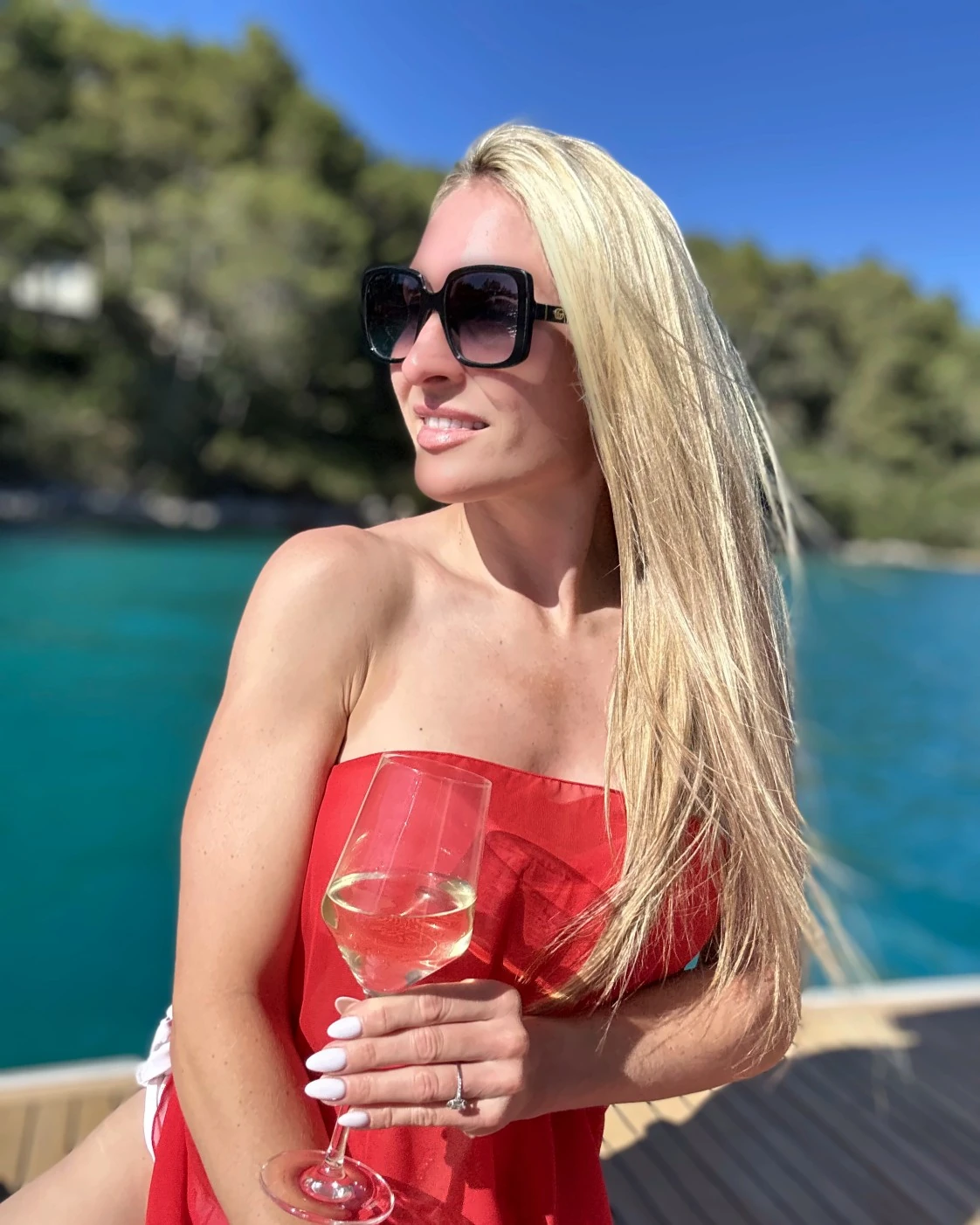 Teresa lächelnd auf einem Boot vor einer türkisen Bucht in Kroatien